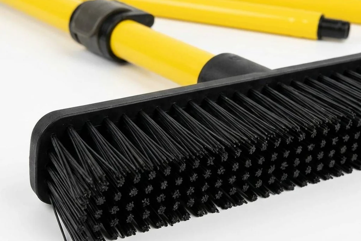 Close view of the FURemover broom's black rubber bristles and yellow handle