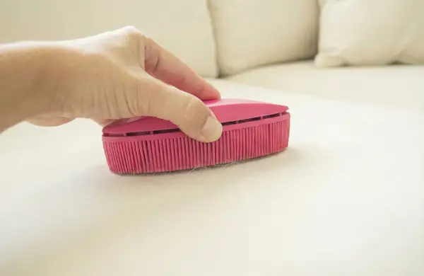 Pink rubber lint brush used on light-colored upholstery